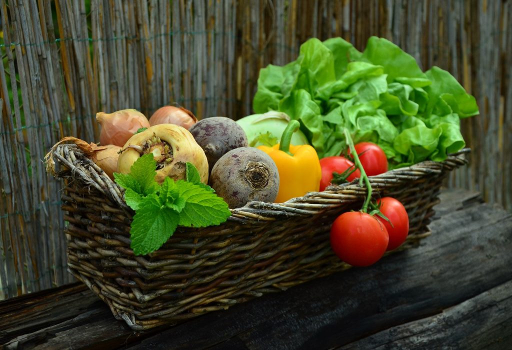 Gemüse (Salatkopf, Paprika, Tomaten, Rote Beete usw.) aus dem eigenen Garten in einem schönen Korb.